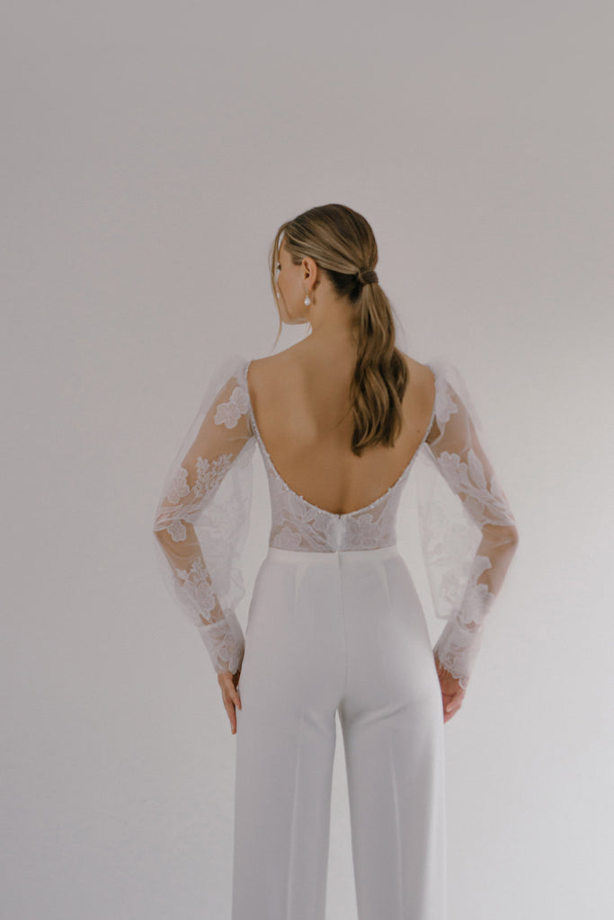 BAR is a cheeky and stylish bridal jumpsuit. The pants have an elegant crease that gives the soft fabric some structure, while the form-fitting top is crafted in tulle and lace, with romantic puffy sleeves.  BAR can be paired with a matching tailored jacket, sold separately, to complete this contemporary ultra-chic vibe.