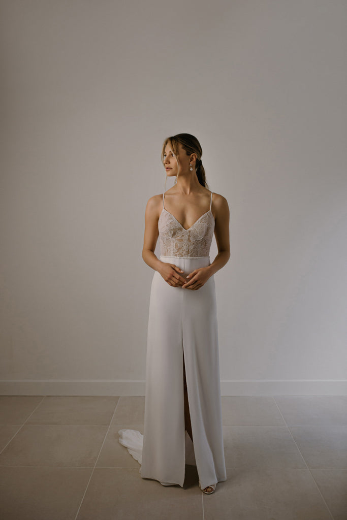 NETI is youthful and effortless, with just the right amount of sexy. NETI is composed of a crisp, satin-lined chiffon slit skirt and a form-fitting strappy lace top. This minimalistic and cool bridal gown can easily be transformed to enhance its romantic appeal, when paired with a sheer lace overtop and skirt, sold separately. The lace overlay features 3D flowers that are simply dreamy!