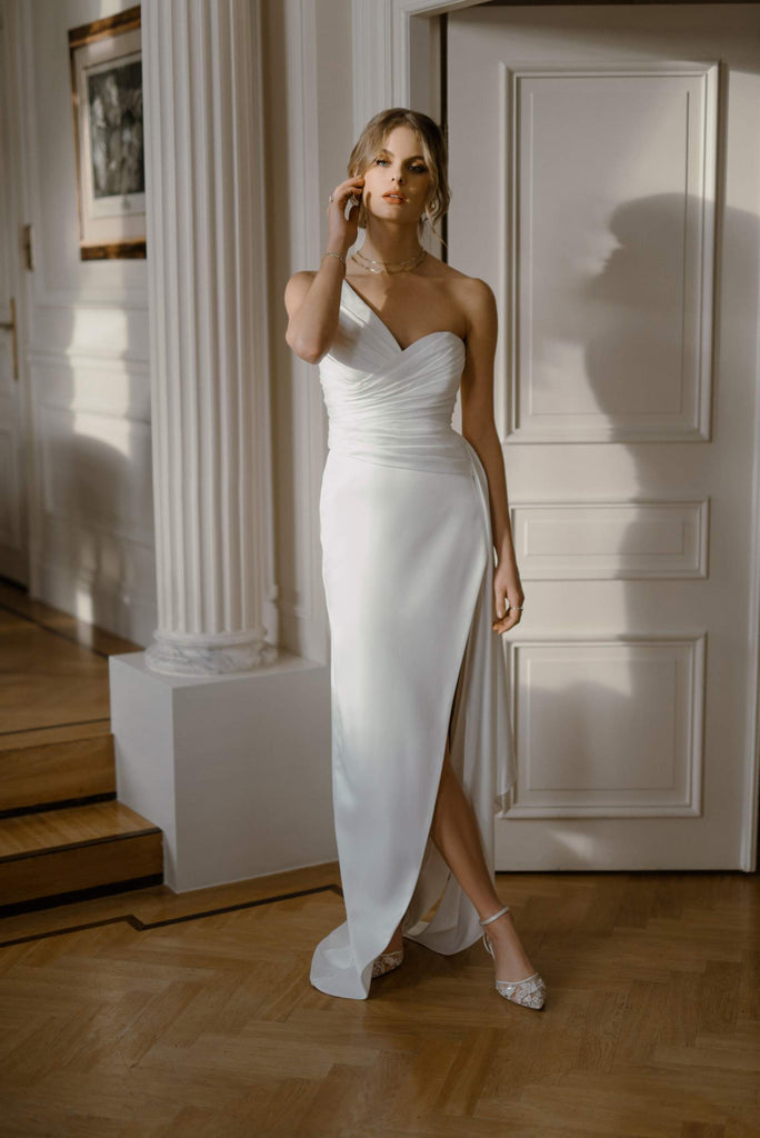 This corset dress is inspired by neoclassicism. The asymmetric corset immediately steals the show, only to be followed by a long dramatic draped volan. This head-turner is fabricated in classic satin, while the slit skirt gives it a modern and sexy siren shape.   LAYLA is eternally elegant, with just the right amount of tease. A classic pick for the sophisticated bride.