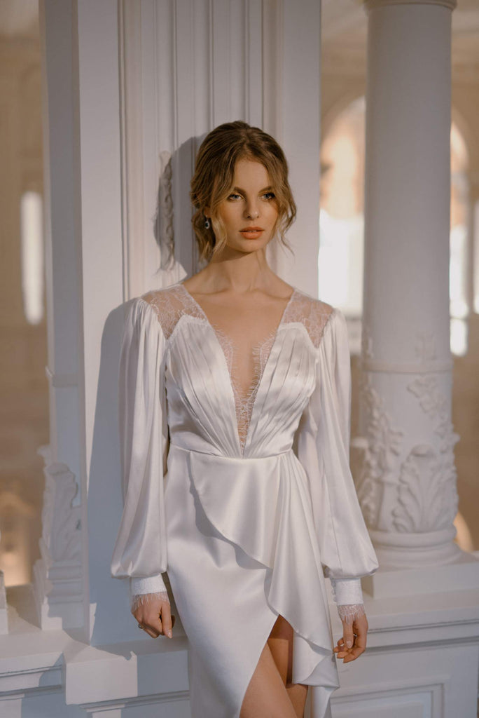 This bridal dress is crafted with elite tailoring. MESHI is draped in layers of silk, creating shell-inspired patterns to fit the alluring wrap cut. Big romantic sleeves and a highly slit skirt compliment the soft and suggestive look.   MESHI is a fashion-forward gown, with soft and seductive movement, making it fit for a bride who enjoys subtle and sexy style. 