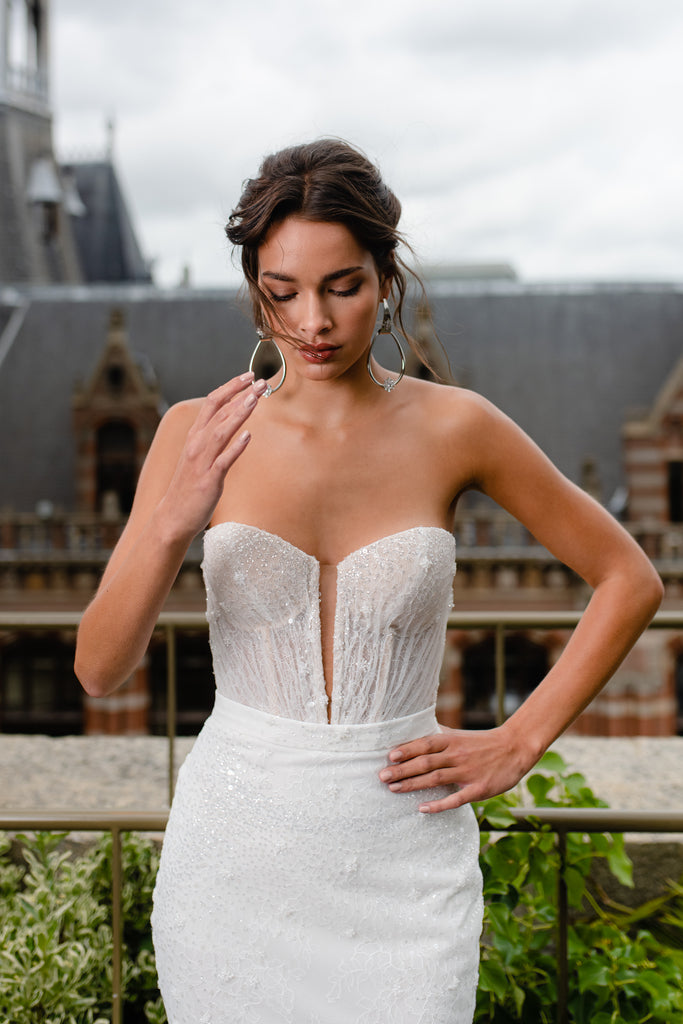 This two-piece wedding gown is a marvel of style. It shimmers ever so slightly thanks to the beaded lace fabric and boasts gentle details which give it a glamorous statuesque look.  The playful and flattering handmade blush cup corset alongside the fitted mermaid skirt will make you feel like a muse.
