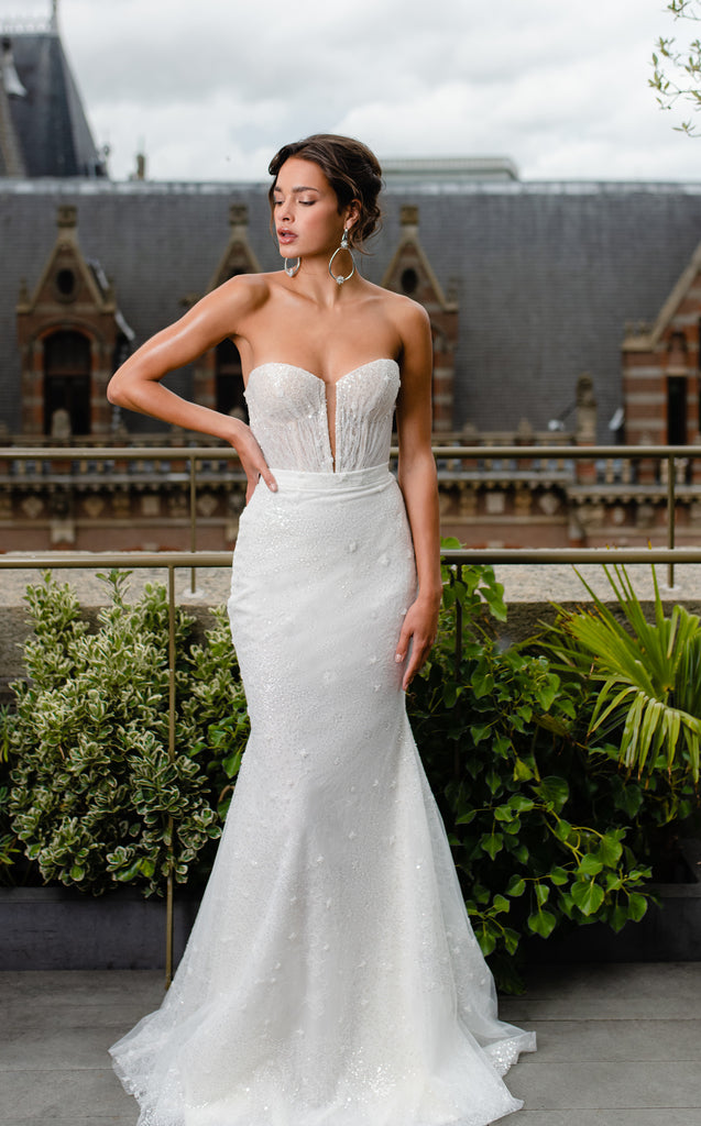 This two-piece wedding gown is a marvel of style. It shimmers ever so slightly thanks to the beaded lace fabric and boasts gentle details which give it a glamorous statuesque look.  The playful and flattering handmade blush cup corset alongside the fitted mermaid skirt will make you feel like a muse.