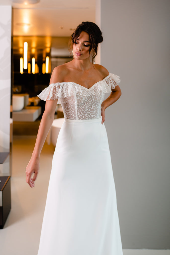 This two-piece bridal gown is a staple of femininity thanks to the unique embroidered corset, adorned with delicate beading and volant detail. Paired with a fitted chiffon skirt, ROSIE is a sure head-turner! You’ll feel superior in this elegant and feminine wedding dress.