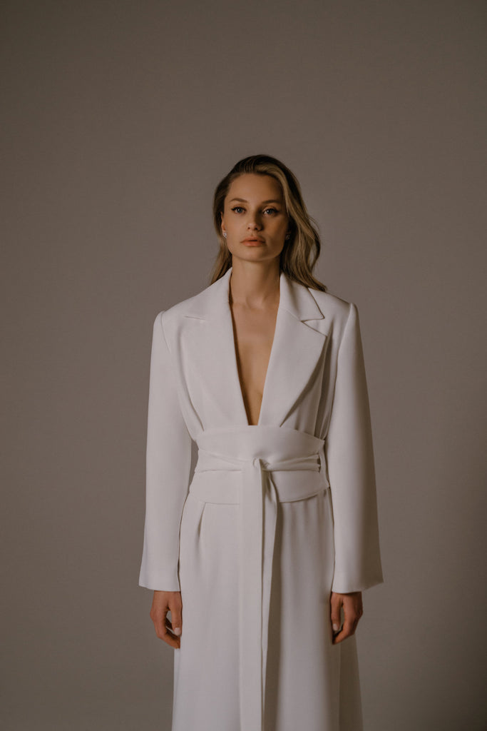 KIREL is a one-of-a-kind long bridal jacket. This high-end, fashion-forward bridal accessory can be paired with multiple different dresses, and instantly transforms the entire look.  KIREL is crafted in a unique crepe fabric and closes with a single small button. The belt, sold separately, is inspired by the timeless beauty of traditional Kimonos, and gives this versatile structured jacket a soft, artisanal, and layered look.