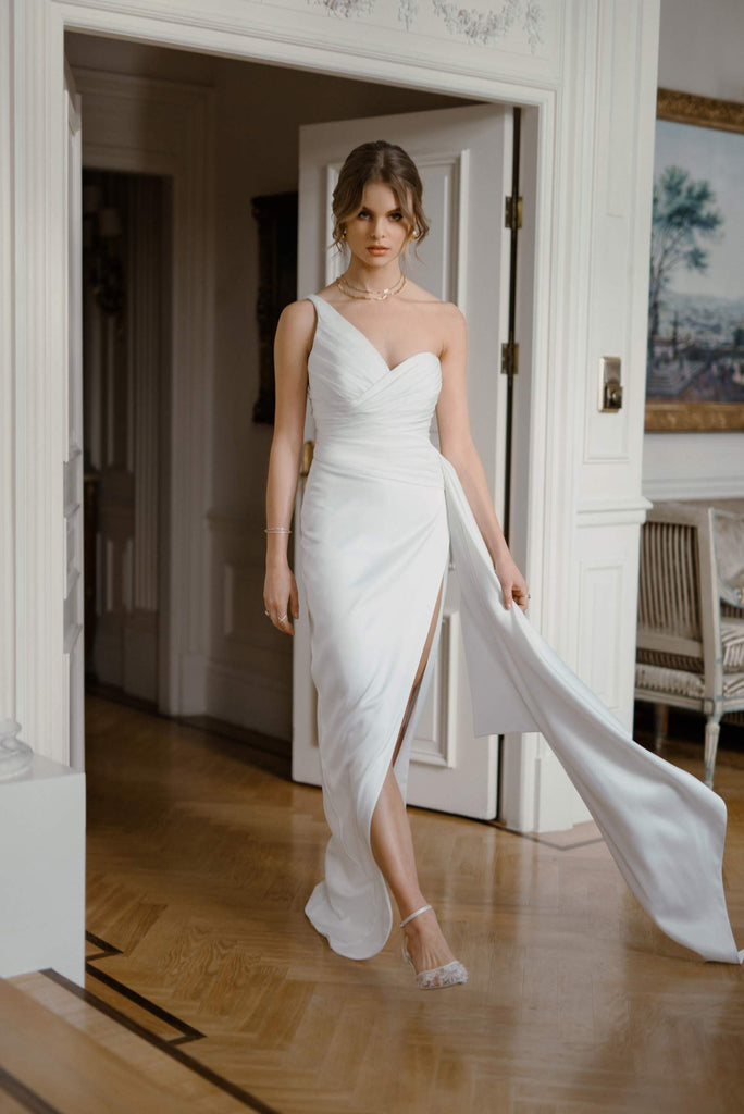 This corset dress is inspired by neoclassicism. The asymmetric corset immediately steals the show, only to be followed by a long dramatic draped volan. This head-turner is fabricated in classic satin, while the slit skirt gives it a modern and sexy siren shape.   LAYLA is eternally elegant, with just the right amount of tease. A classic pick for the sophisticated bride.