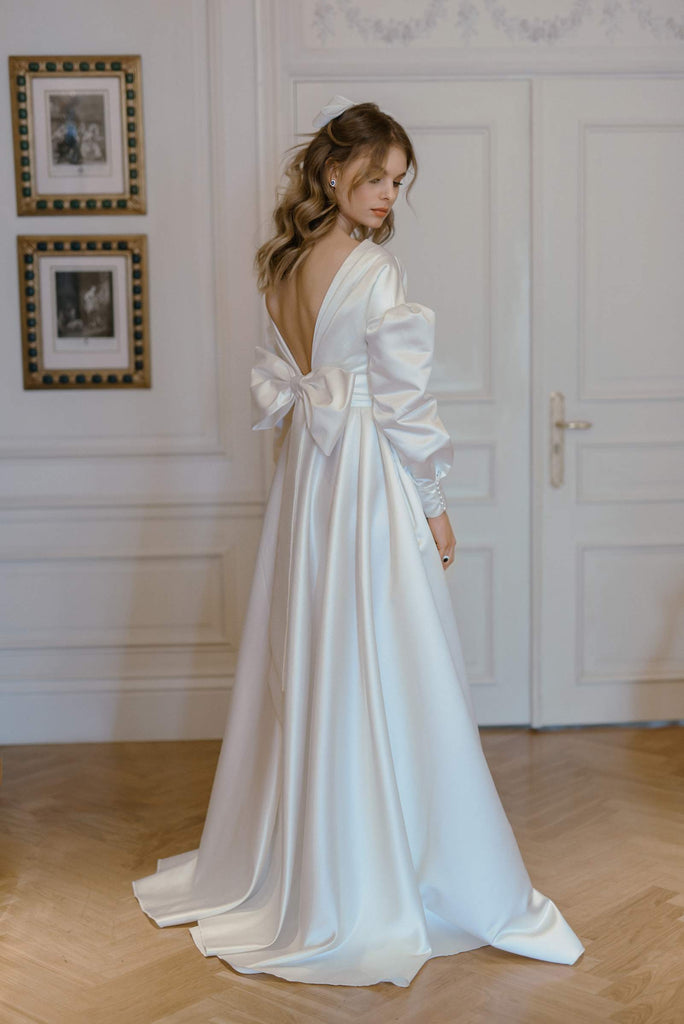 This ultra-romantic vision is made entirely from luxurious satin. LUCY features pompous sleeves, a cloche skirt, and a wide structured belt which gives the dress a flattering and gathered shape.   This dress is reimagined romantic nostalgia, fit for the fashion-forward bride who’s inspired by timeless tales of love.