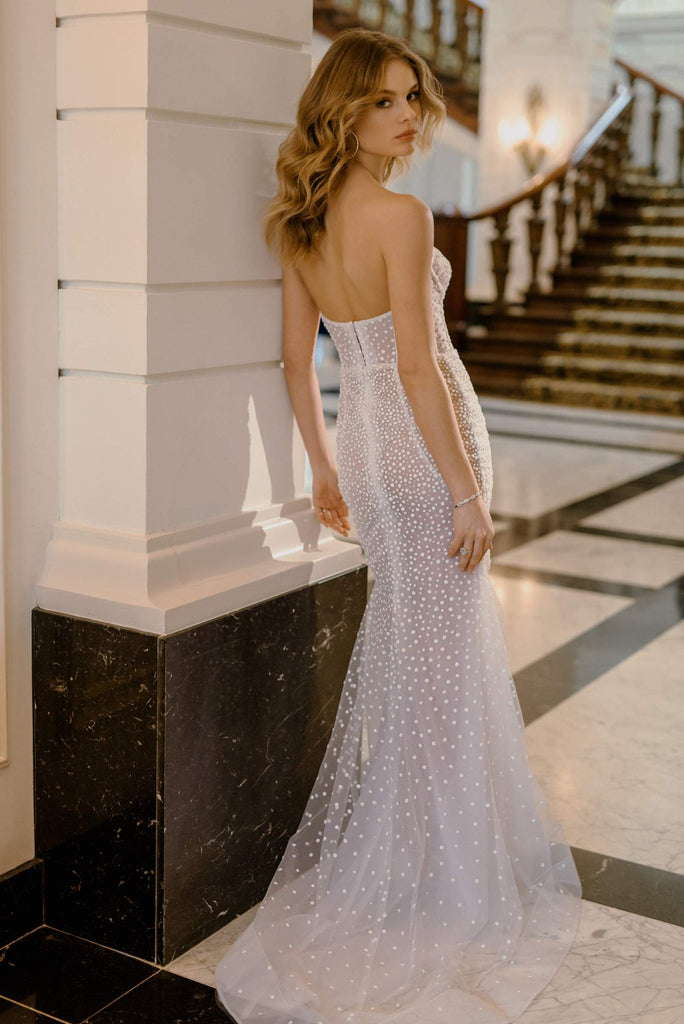 PERRY is a flirtatious and daring Wedding Dress. This dress is fabricated with sheer dotted tulle, featuring cutout elements, a structured corset and a middle slit.  This dress is the perfect match for a bold and confident bride, who wants to appear especially statuesque on her special day.